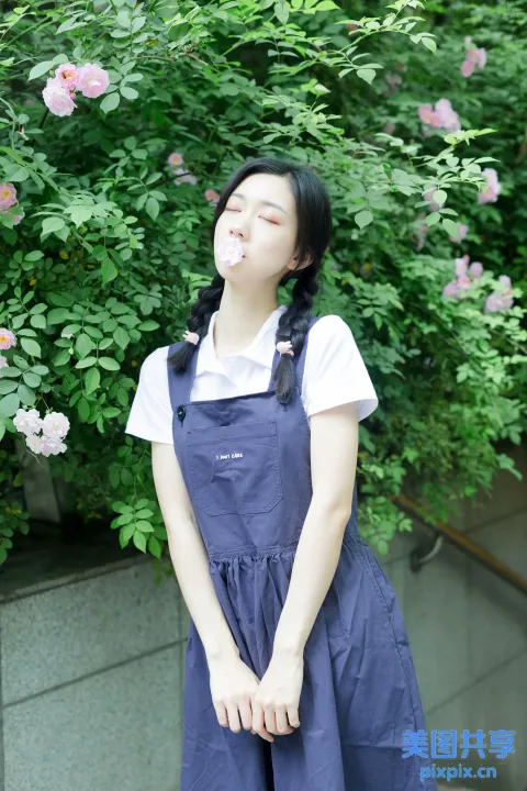 有个女人站在开花的灌木丛前