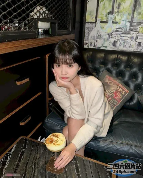 有个女人坐在沙发上，手里拿着一杯咖啡