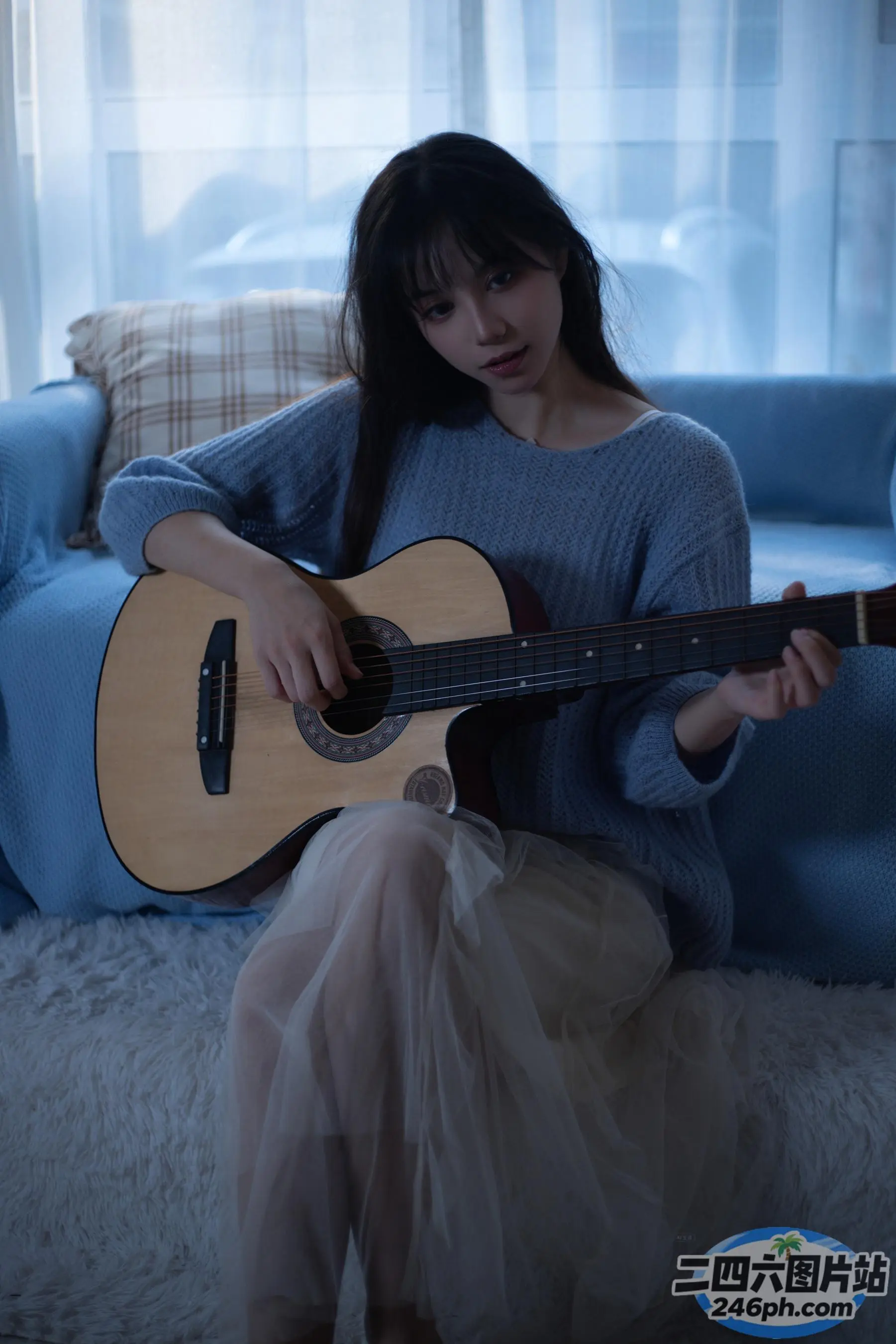 坐在沙发上弹吉他的 arafed 女人