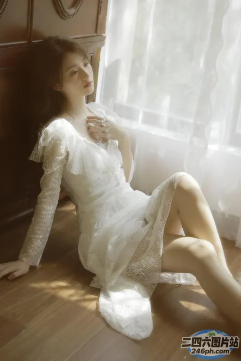 坐在地板上穿着白色连衣裙的 Arafed 女人