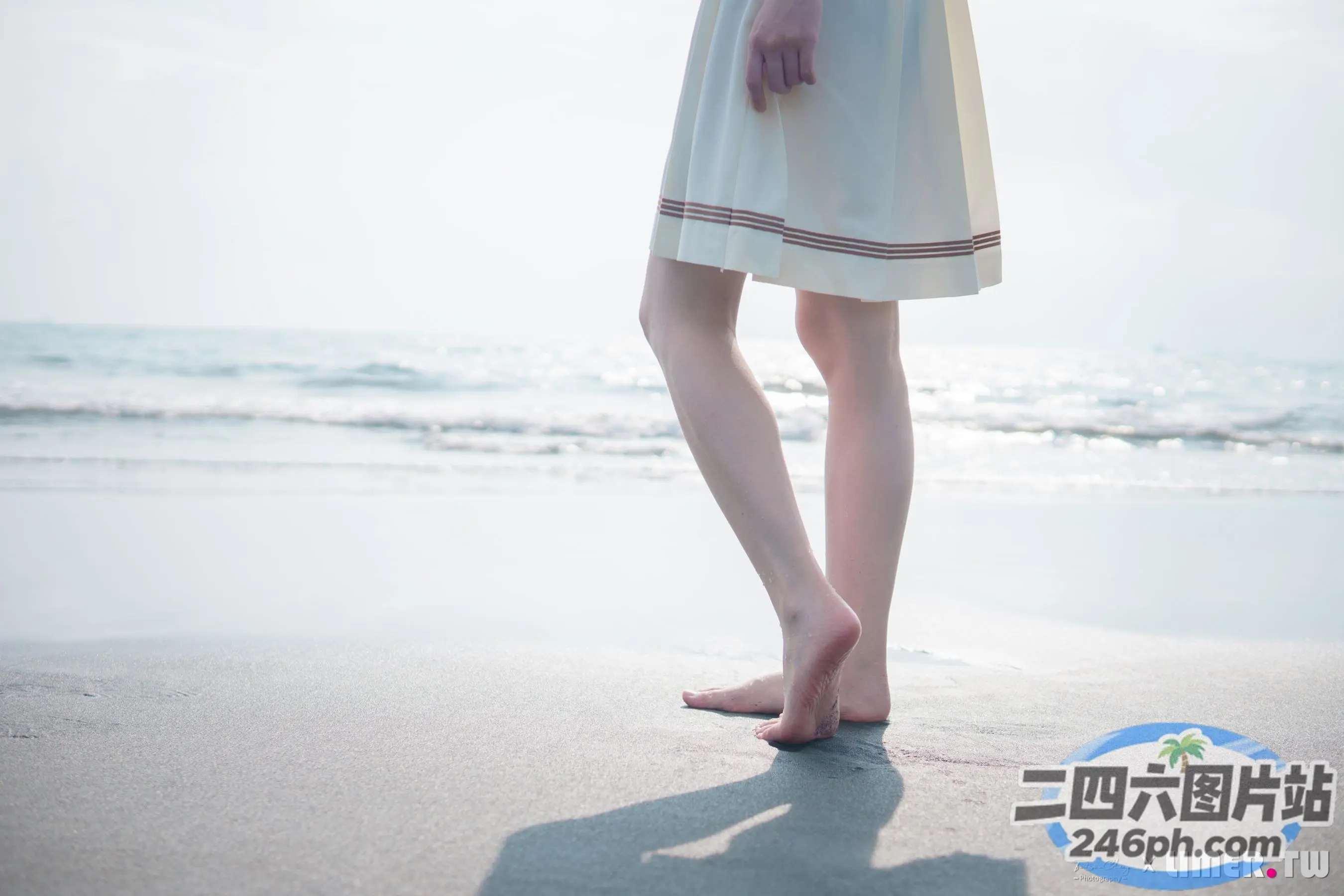 有一个女人站在沙滩上，双脚踩在沙子里