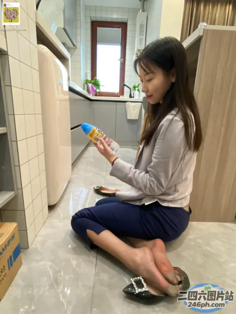 坐在地板上的女人拿着一瓶水和一部手机