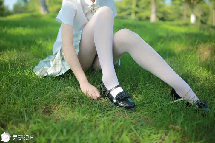 草地上坐着一个女人，穿着裙子和鞋子