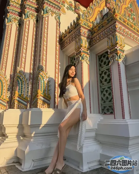 一名身穿白色连衣裙的女子在一栋建筑前摆姿势