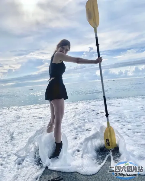 一名身穿黑色连衣裙的女子站在冲浪板上