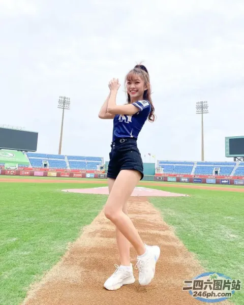 棒球场上穿着蓝色衬衫和黑色短裤的 arafed 女孩