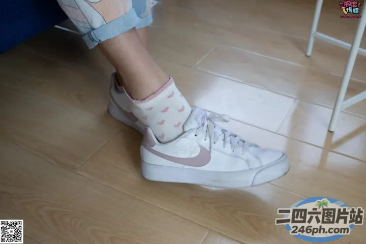 有人穿着白色运动鞋和粉红色袜子坐在木地板上